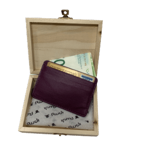 ארנק עור קטן בצבע סגול בורדועמוק בתוך קופסת עץ בהירה ופתוחה