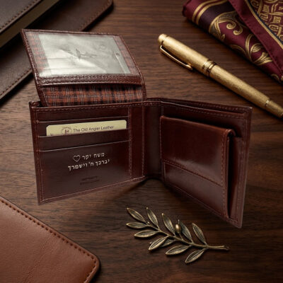 ארנק עור חום לגבר עם הקדשה אישית "משה יקר יברכך ה' וישמרך" על רקע עץ יוקרתי עם עט נובע מוזהב.