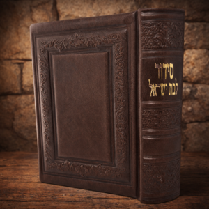 סידור תפילה מעור חום עם הטבעה אומנותית וכתב זהב, עומד על משטח עץ ורקע אבן חמים