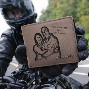 ארנק עור חום עם חריטה אישית מוחזק ביד של רוכב אופנוע על כביש פתוח