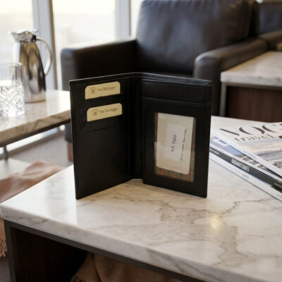 צילום תקריב של ארנק עור פתוח על שולחן שיש לבן, עם מגזינים וקנקן קפה ברקע מטושטש.