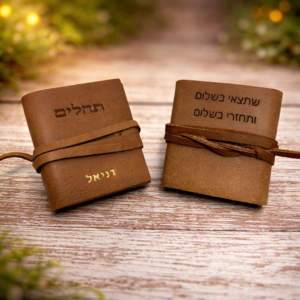 ספרי תהילים מעור עם חריטה אישית, מונחים על רקע עץ טבעי ואור חמים