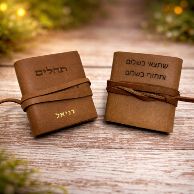 ספרי תהילים מעור עם חריטה אישית, מונחים על רקע עץ טבעי ואור חמים