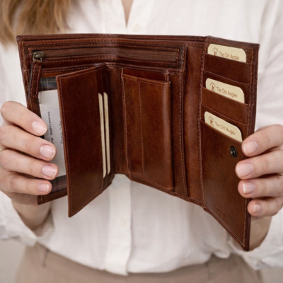 אישה אוחזת בארנק נשים חום מעור איטלקי פתוח עם תאים לכרטיסים ולשטרות