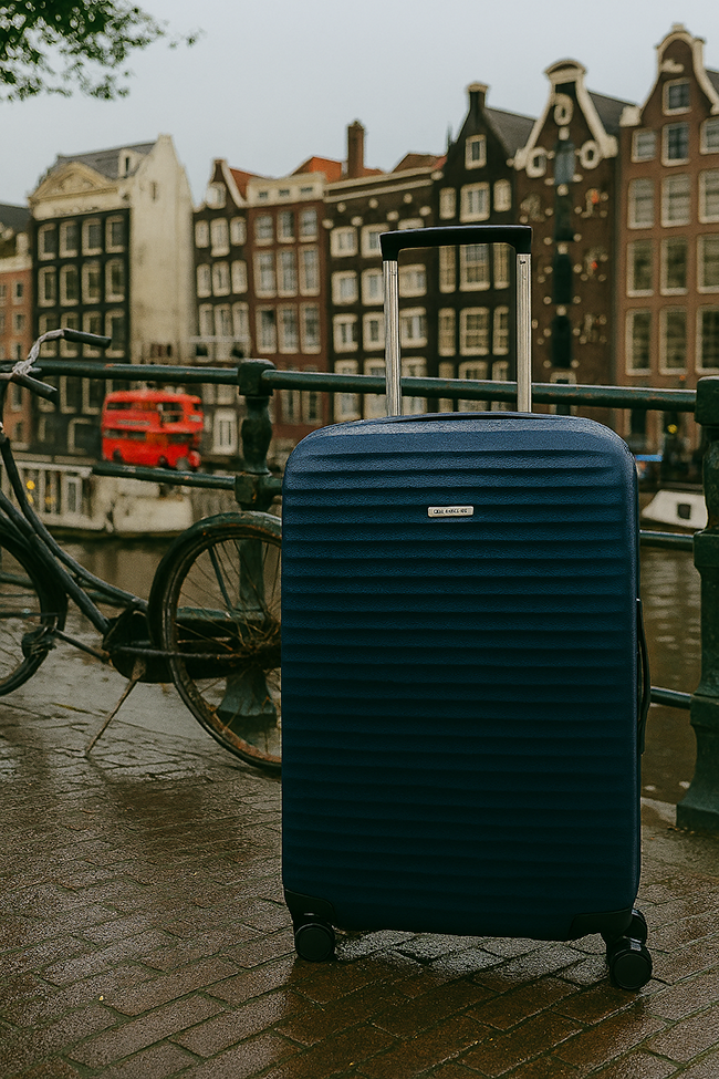 מזוודת Samsonite עמידה על רקע תעלות אמסטרדם המפורסמות והבתים הצרים.