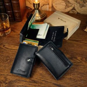 ארנק עור שחור עם מנגנון כרטיסים קופצים, כרטיסי אשראי ושטרות, מונח ליד קופסת עץ יוקרתית