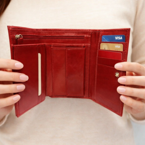 אישה אוחזת בארנק נשים אדום מעור איטלקי פתוח עם תאים לכרטיסים ולמטבעות