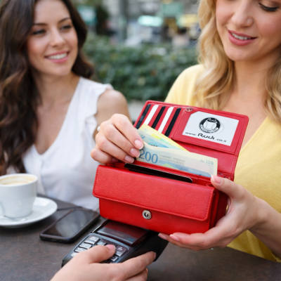 אישה יושבת בבית קפה ומשלמת עם ארנק נשים אדום מעור של RUDI