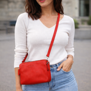 אישה עם תיק צד קטן לנשים בצבע אדום מעור, תיק קומפקטי עם רצועת כתף