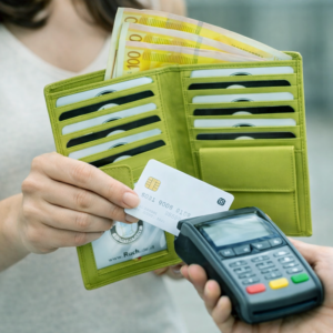 אישה משלמת בכרטיס אשראי מארנק נשים מעור ירוק עם חריצי כרטיסים פתוחים