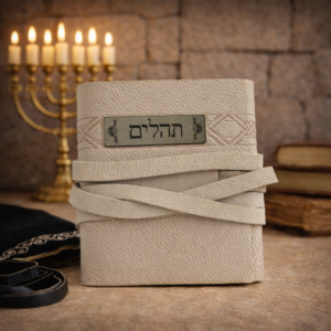 ספר תהילים מעור בהיר עם רצועת עור, מונח על רקע מנורה וספרי קודש באווירה יהודית רוחנית