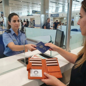 אישה בדלפק צ׳ק אין בשדה תעופה משלמת עם ארנק נשים מעור של RUDI