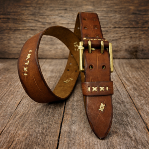 חגורת עור חומה בעבודת יד עם אבזם מתכתי על רקע עץ טבעי