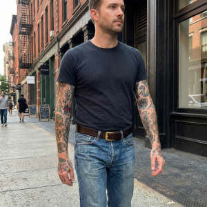 חגורת עור חומה איכותית לגבר מגולגלת על רקע לבן