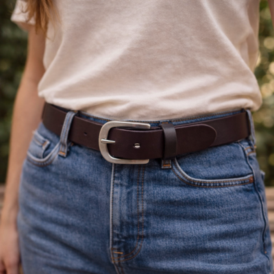 חגורת עור לנשים בצבע חום עם אבזם מתכת על ג'ינס בהיר