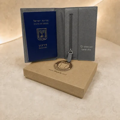 נרתיק לדרכון מעור אפור פתוח עם תא רוכסן והטבעה אישית בכסף לצד דרכון ישראלי