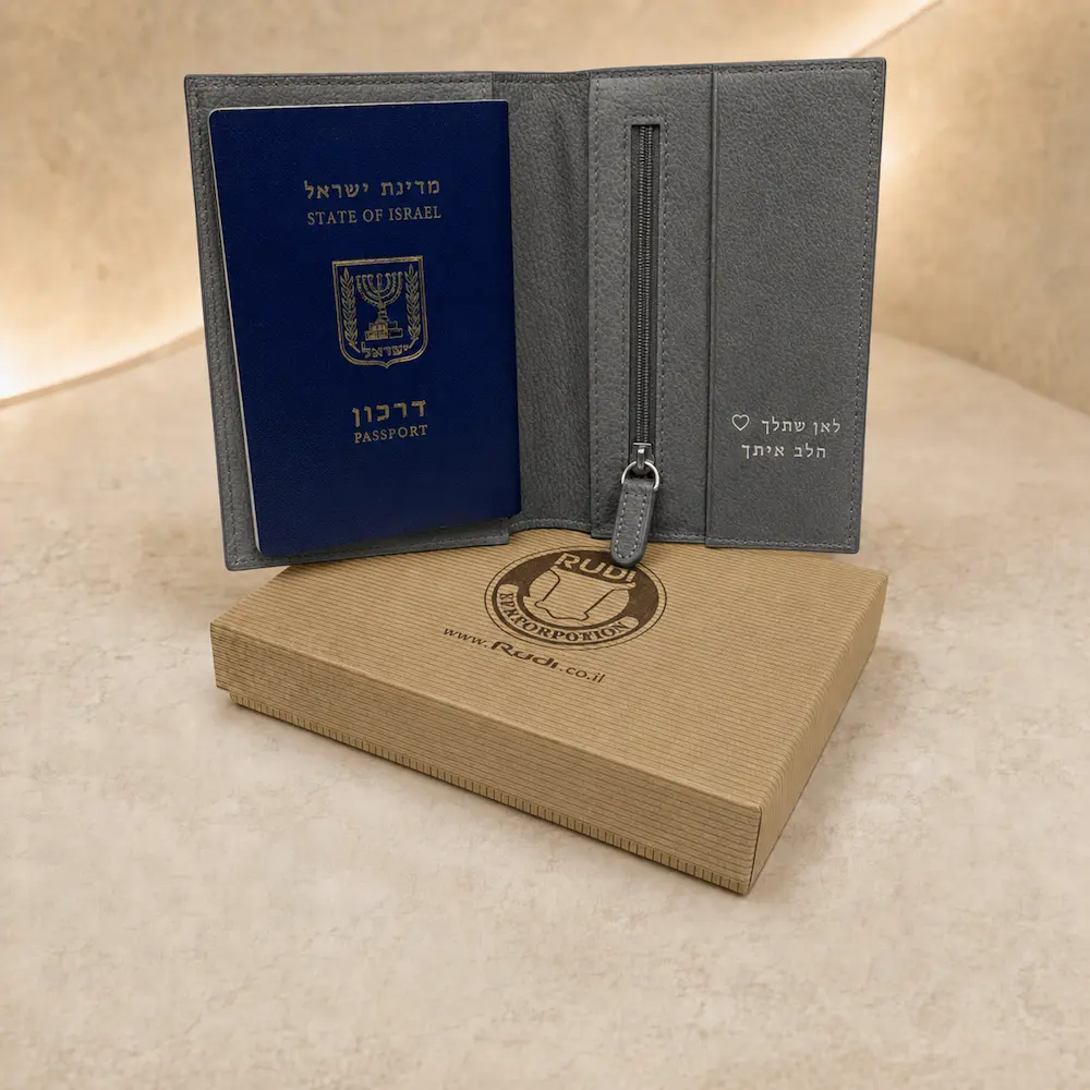 נרתיק לדרכון מעור אפור פתוח עם תא רוכסן והטבעה אישית בכסף לצד דרכון ישראלי