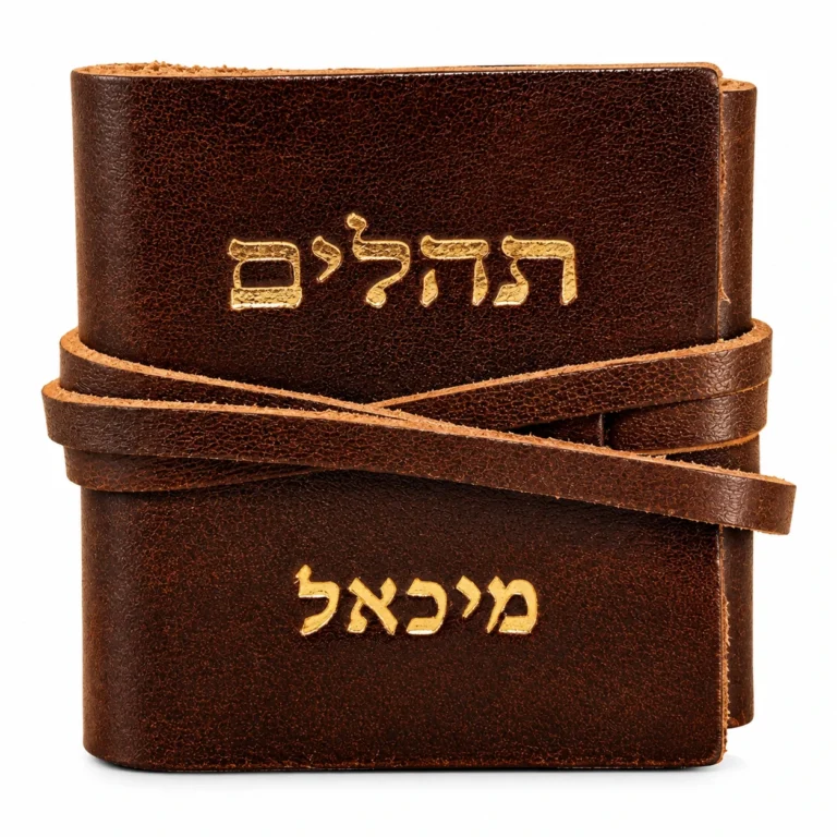 ספר תהילים קטן בכריכת עור חומה עם רצועת עור כרוכה, המילה תהילים והשם מיכאל מוטבעים בזהב על הכריכה